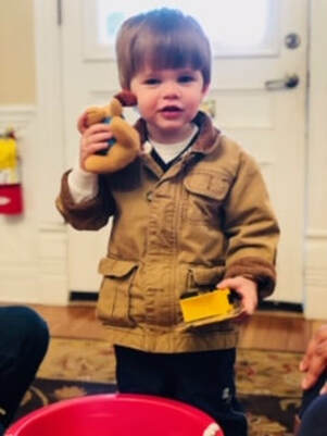 Photo of little boy holding toys inside library