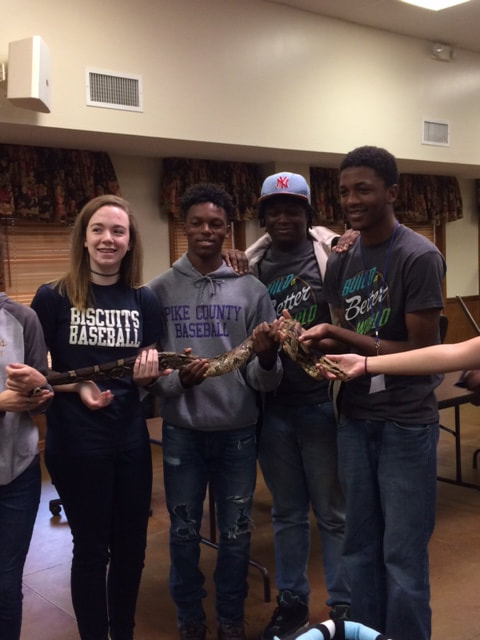 Photo of teen volunteers holding a snake together at a Summer Reading Program event